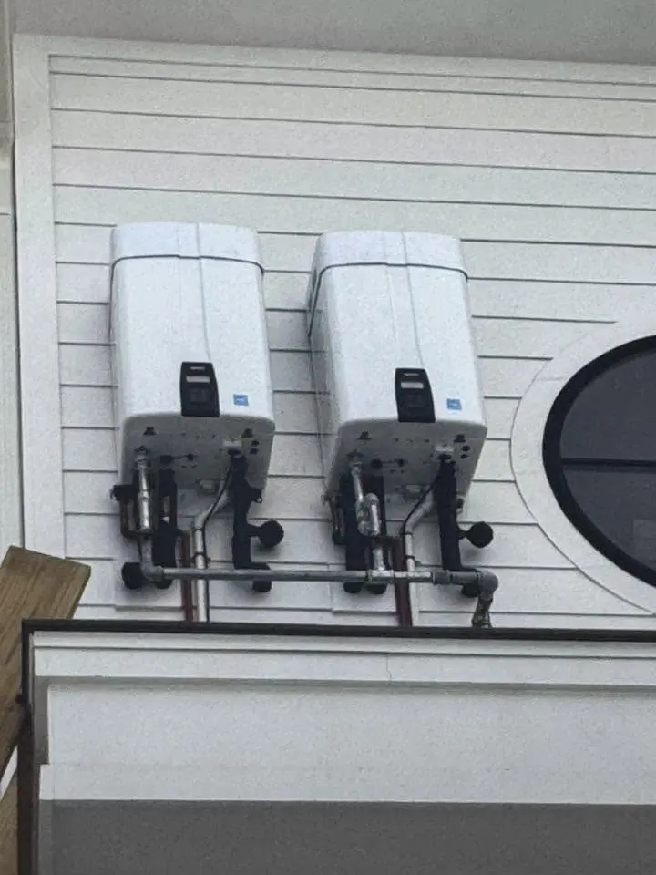 Two tankless water heaters mounted on an exterior wall