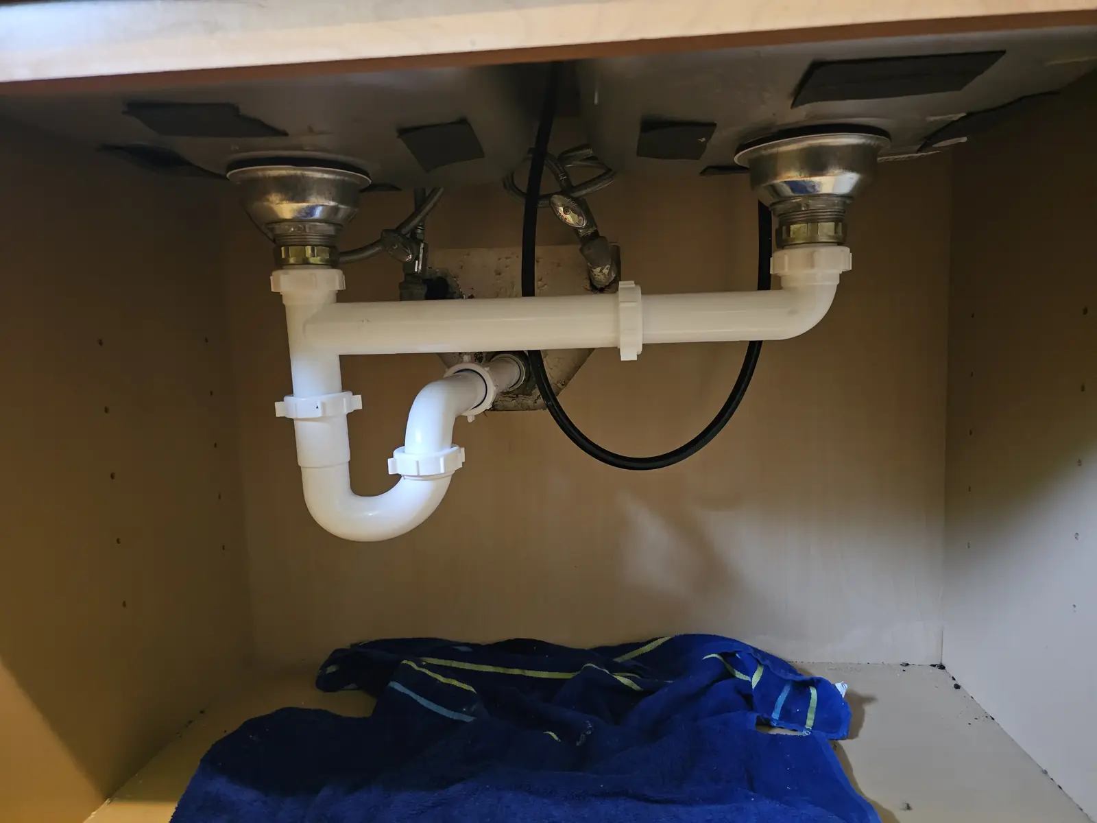 After: new white PVC drain trap installed under the same kitchen sink
